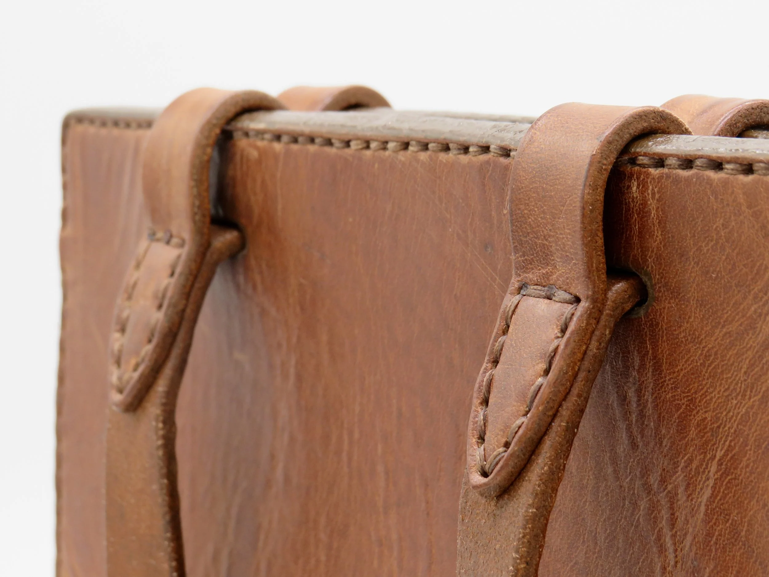 Close-up of a brown leather briefcase handle and edge.