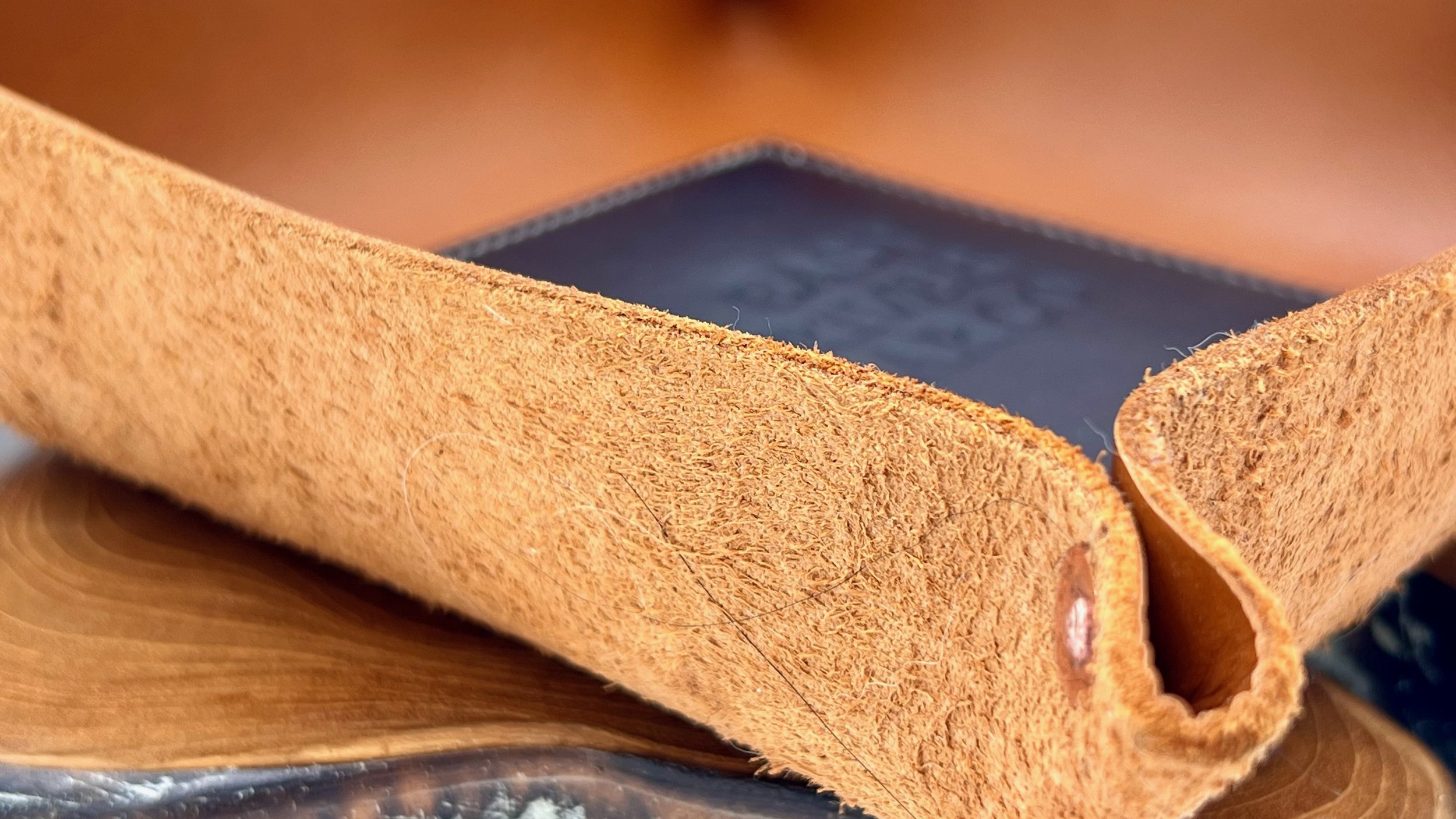 Close-up of a leather valet tray, lying on a wooden surface.
