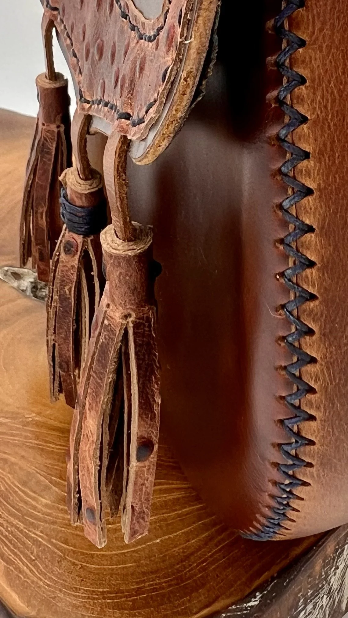 Close-up of a leather and wood Native American headdress with intricate beadwork and feathers.