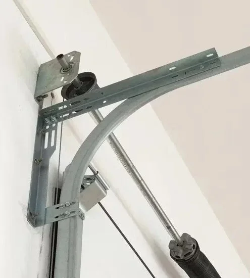 Garage door opener mechanism with metal tracks, a motor, and cables mounted on a wall.