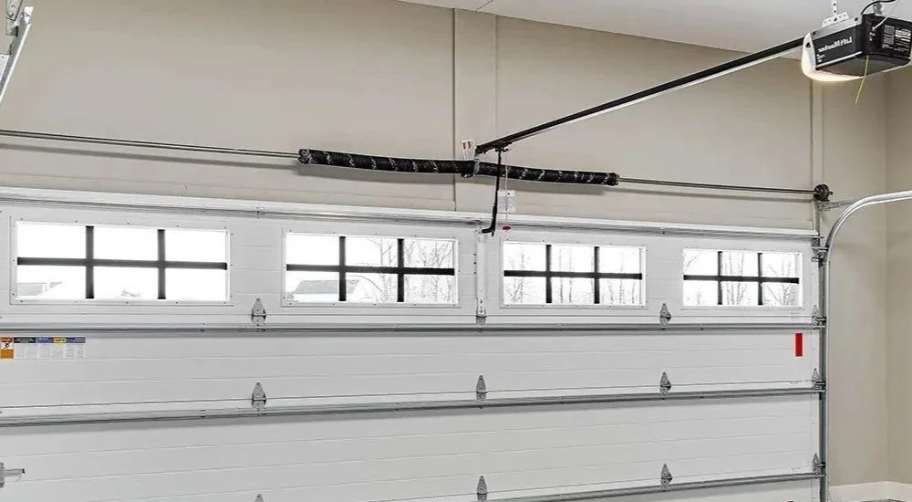Empty garage door with windows, garage ceiling with garage door opener and tracks