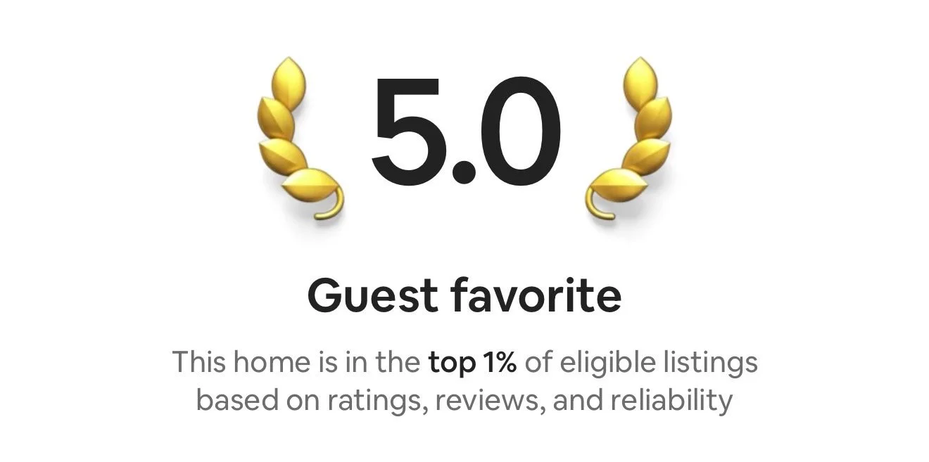 House rating badge with gold laurel wreaths, a 5.0 star rating, and text indicating it is a guest favorite and in the top 1% of eligible listings.