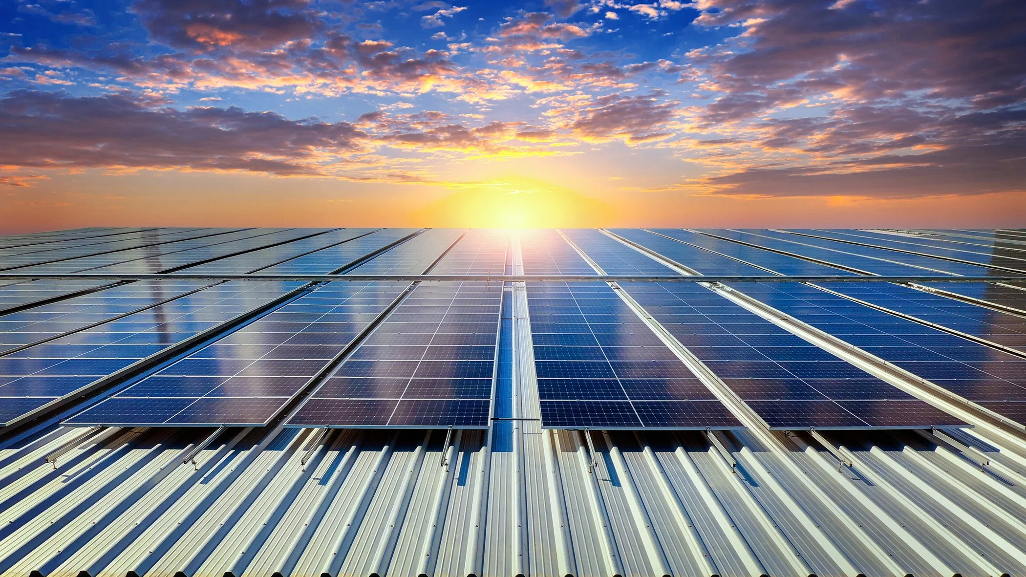 Solar panels installed on a roof during sunset with a partly cloudy sky.