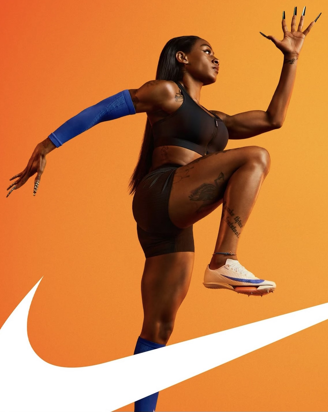 Une femme athlétique en vêtements de sport noirs pose contre un fond orange avec un logo blanc de Nike. Elle porte un bandage bleu sur le bras et des chaussures de course blanc et bleu.