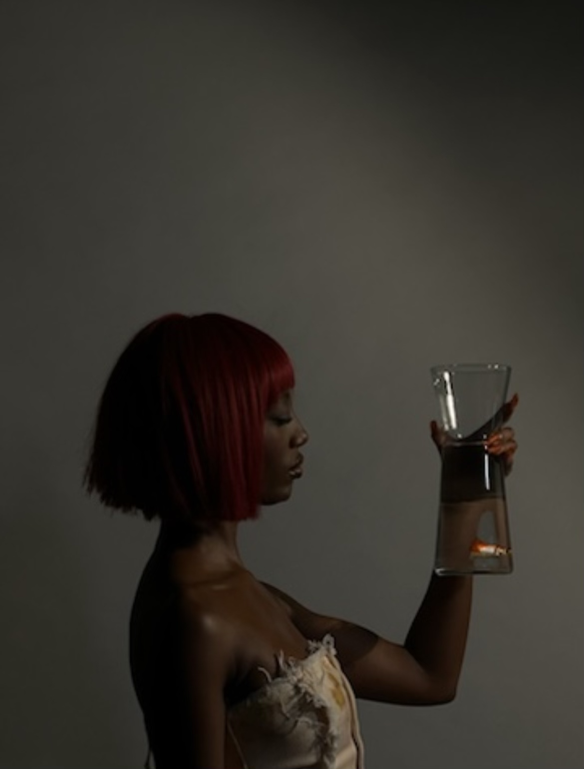 Femme aux cheveux rouges tenant un verre d'eau.