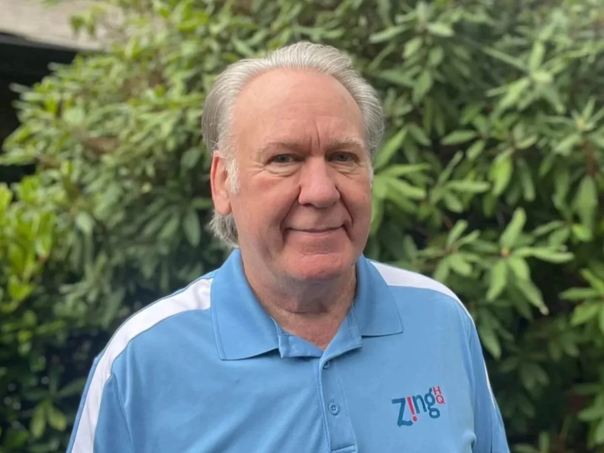 Photo of Zing HQ owner, Jeff Hoerth, standing outside. He is wearing a bright blue polo with white strips on the sleeves and an embroidered Zing HQ logo.
