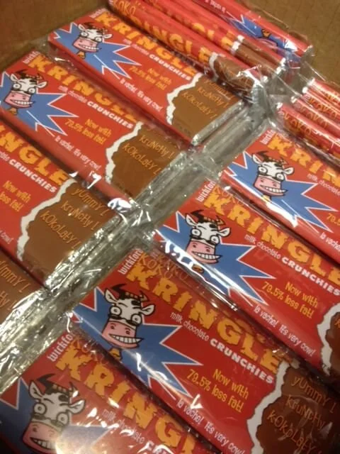 A big stack of chocolate bars wrapped with custom branded label that reads "Kringle" and has a cow cartoon on the front.