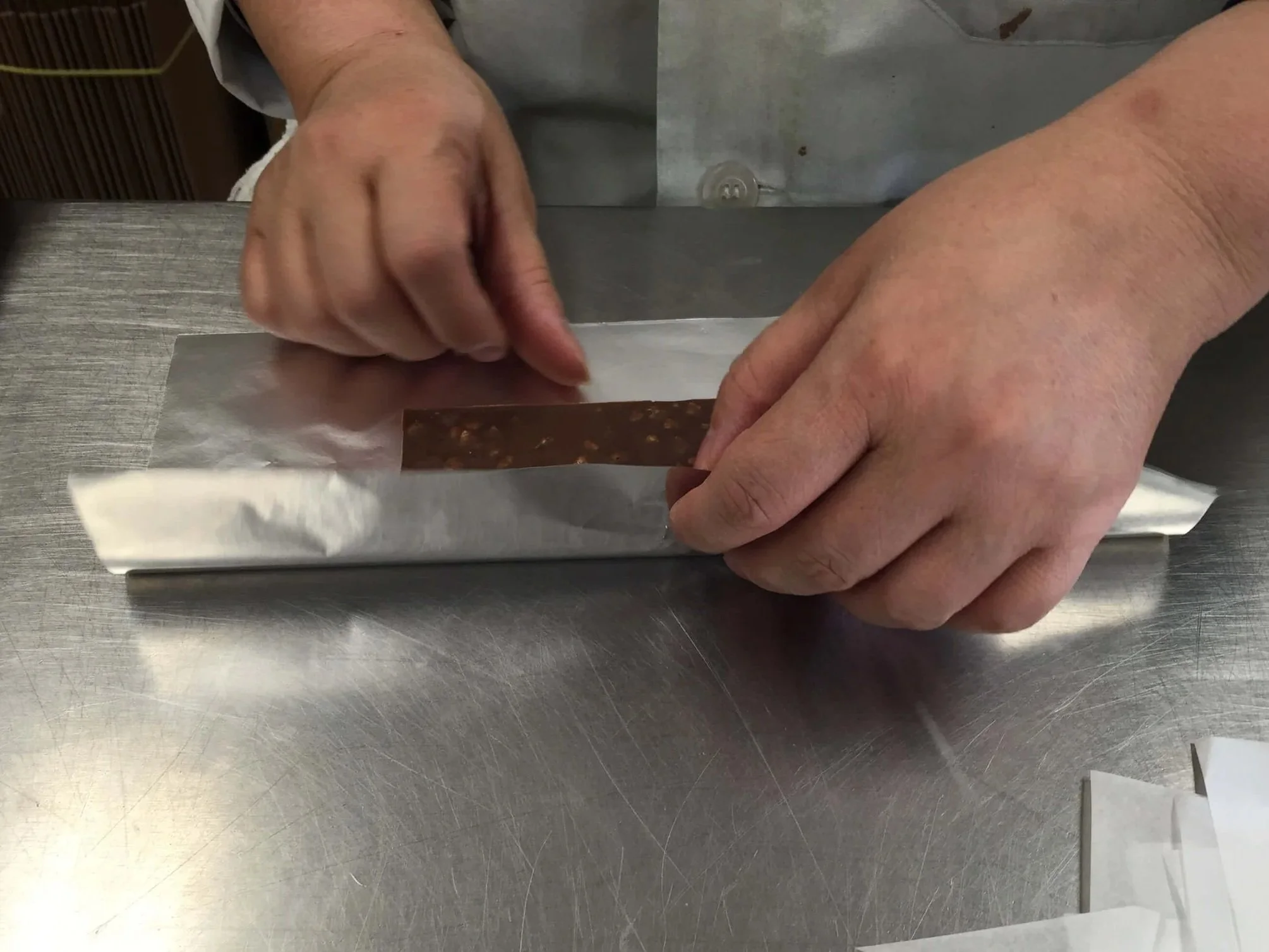 Someone's hands wrapping up a chocolate bar in the alumninum foil.