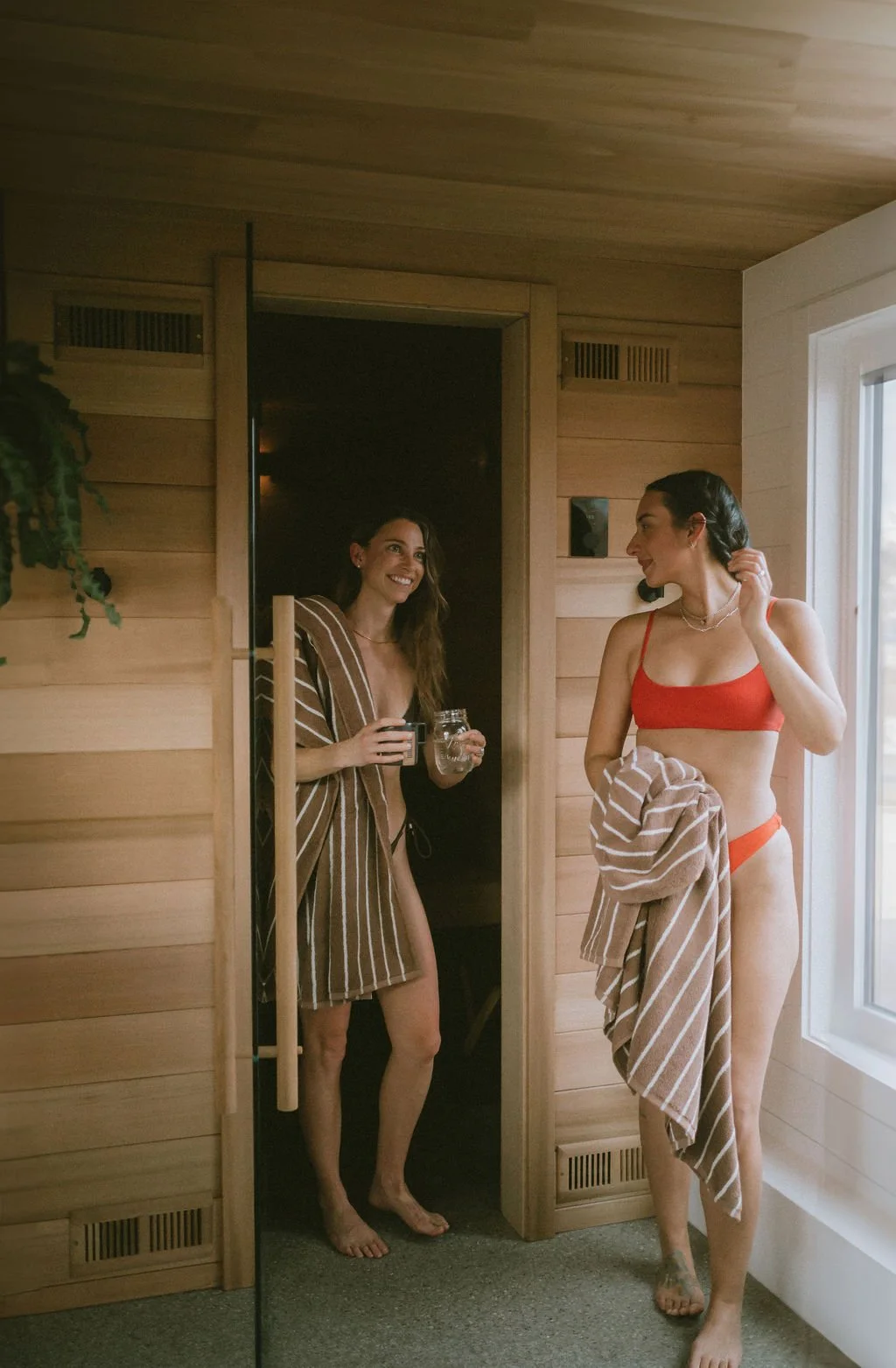 Two women in bikinis chatting inside the Nordica Haus sauna—steam, warmth, and authentic Hood River wellness connection.
