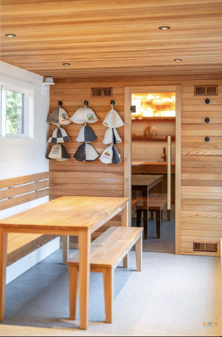 Warm wooden lounge room at Nordica Haus with benches, hats, and soft lighting—Scandi-inspired calm before or after a Hood River sauna session.