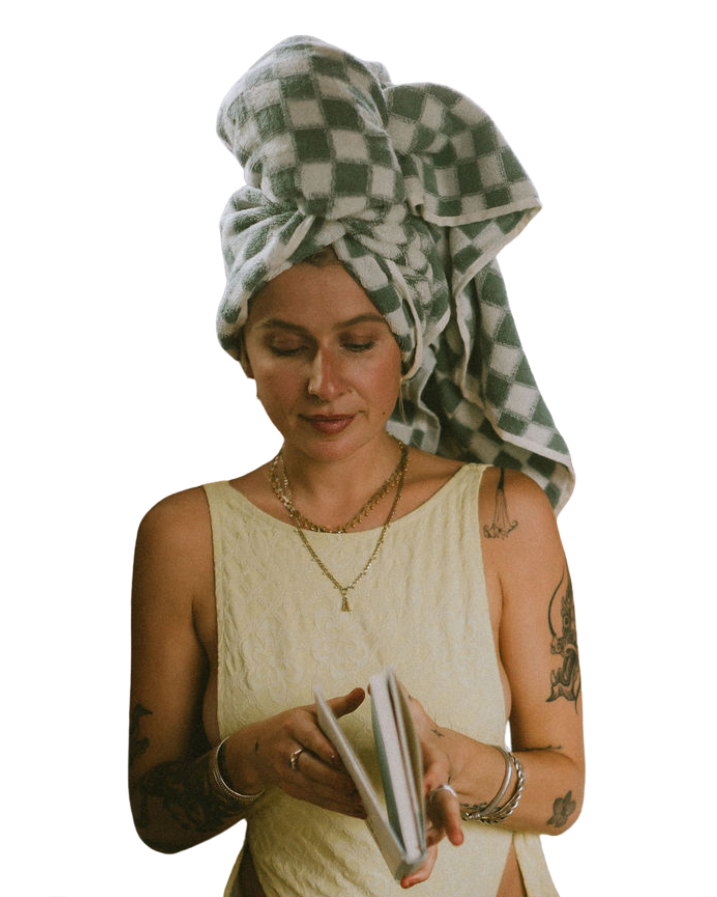 Tattooed woman in a yellow bathing suite with a towel-wrapped head checking her phone inside Nordica Haus—laid-back, stylish, and sauna-ready.