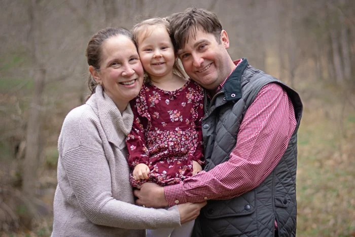 Jessica and her family, outdoors during autumn, smiling and hugging each other.