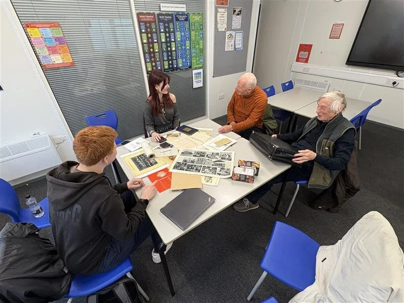 People sat around a table discussing, with papers on the table.