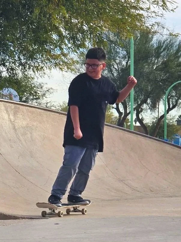 A young boy skateboarding at a skate park during the daytime.
