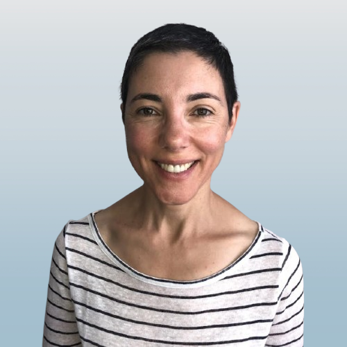 Portrait of a woman with short dark hair, smiling, wearing a striped shirt, against a plain blue background.