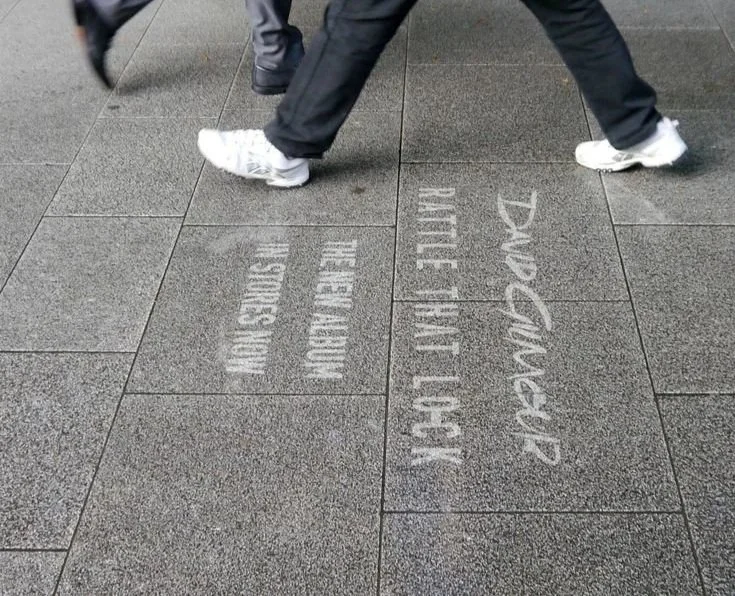 Branded sidewalk decals installed along busy urban walking paths