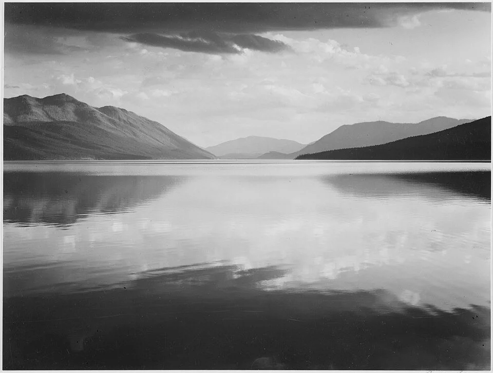 Evening, McDonald Lake, Glacier National Park (1942) by Ansel Adams. Dramatic landscape with dark clouds over the lake. Public domain image from National Archives.
