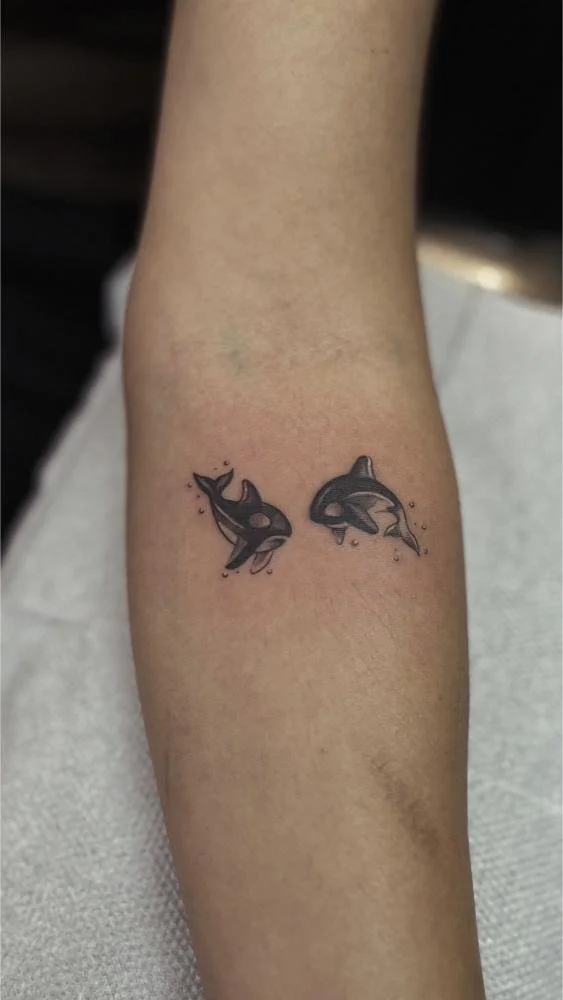 2 dolphins on arm tattoo