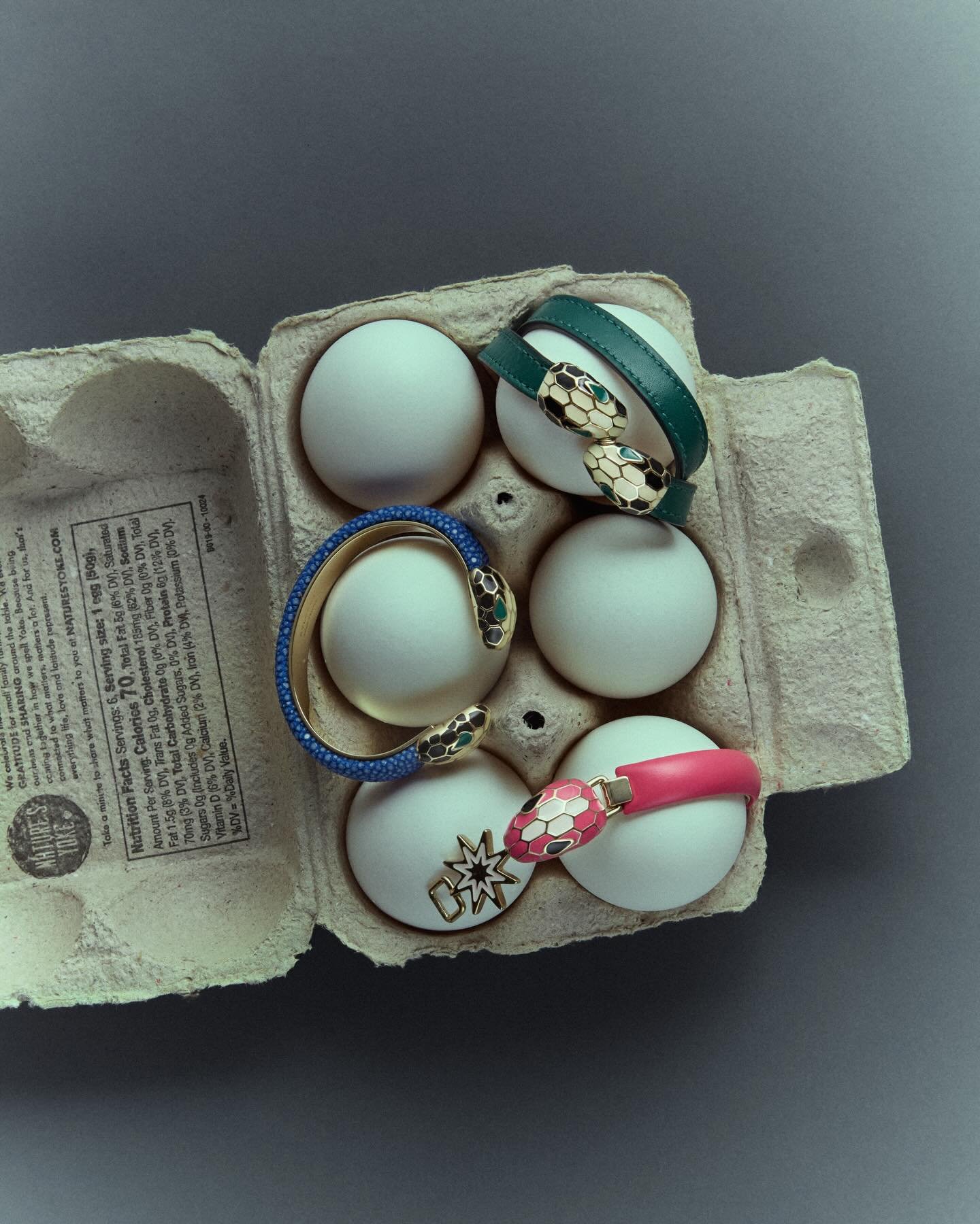 Egg carton containing decorative bracelets and charms with various colors and designs.
