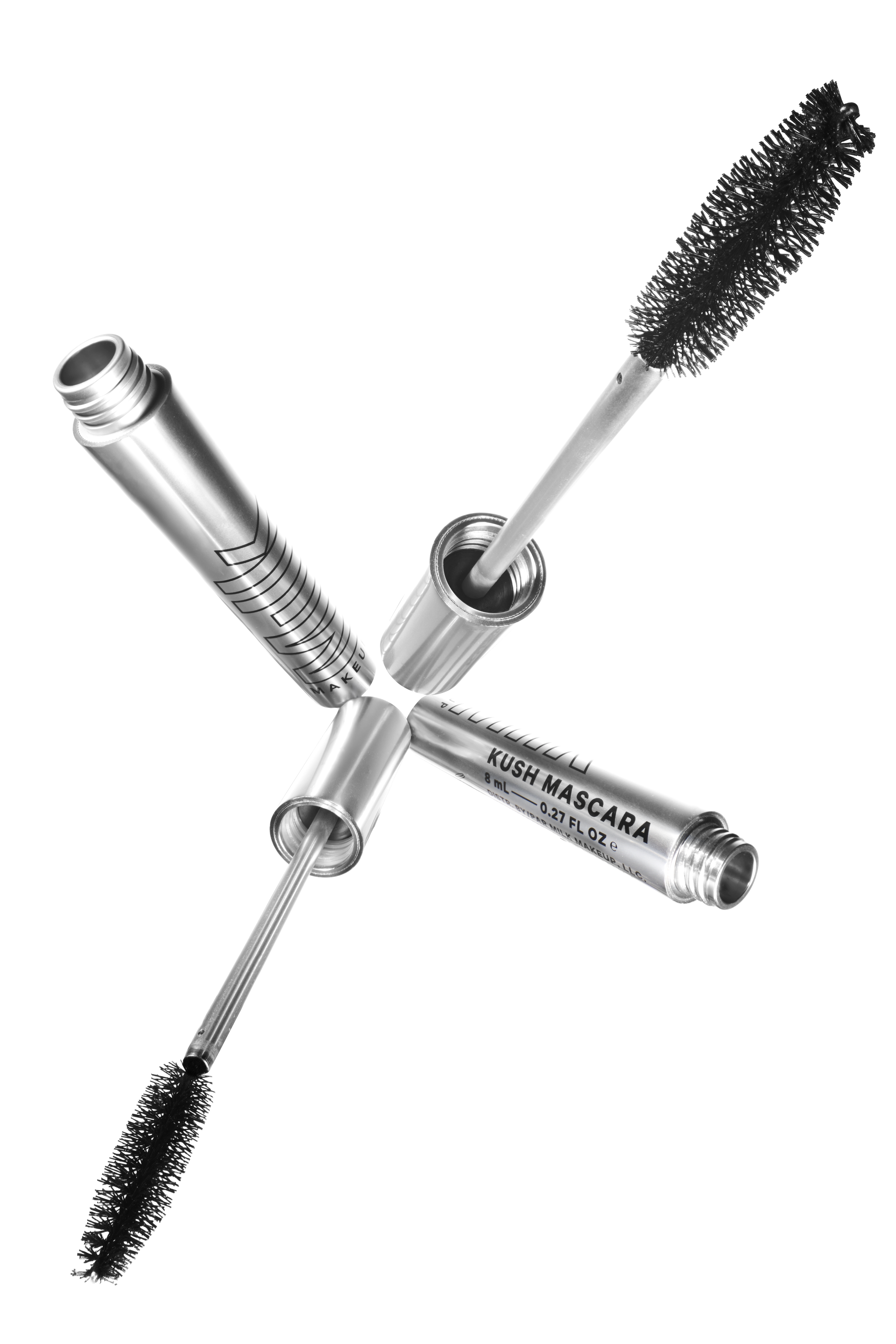 Three silver-colored tubes of Kush Mascara and a mascara wand with a black spoolie brush, arranged in a star shape on a white background.