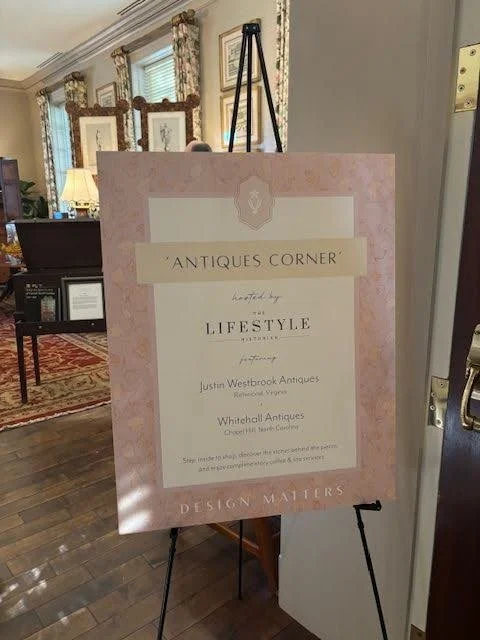 Sign on an easel in an antique store named 'Antiques Corner' with details about the store and its owners.