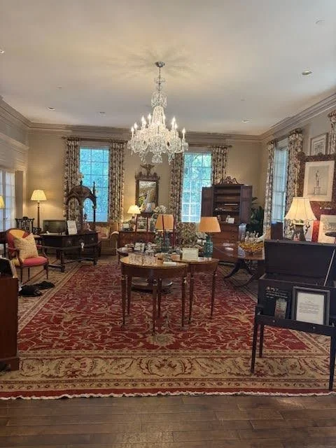 Elegant living room with chandelier, antique furniture, and large windows.