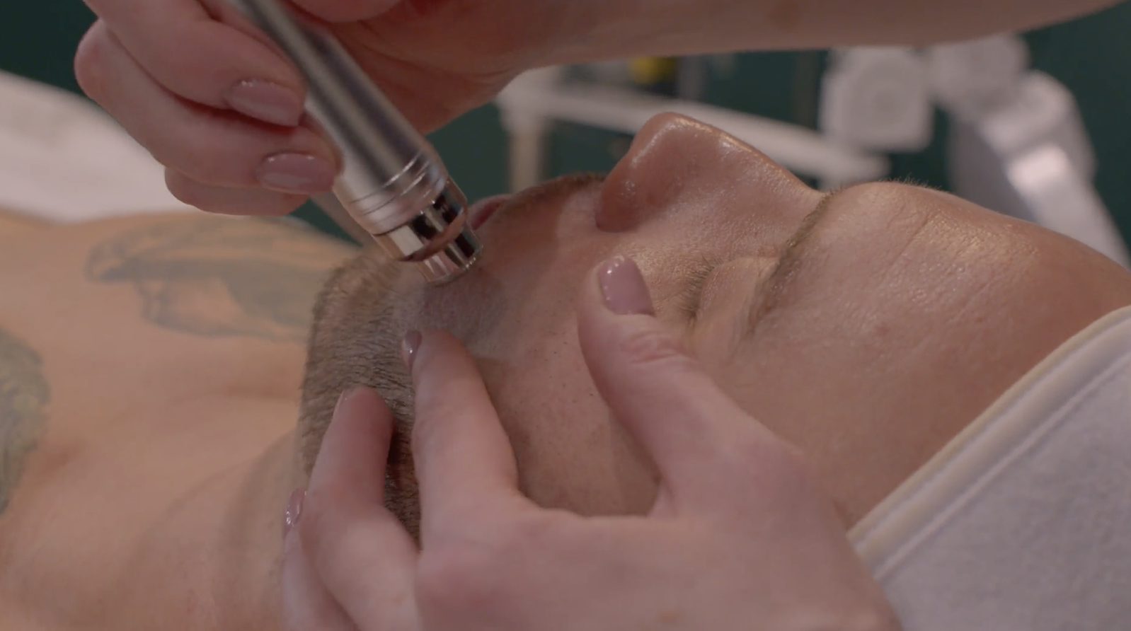 A person receives a facial treatment using a handheld device on their face while lying down.