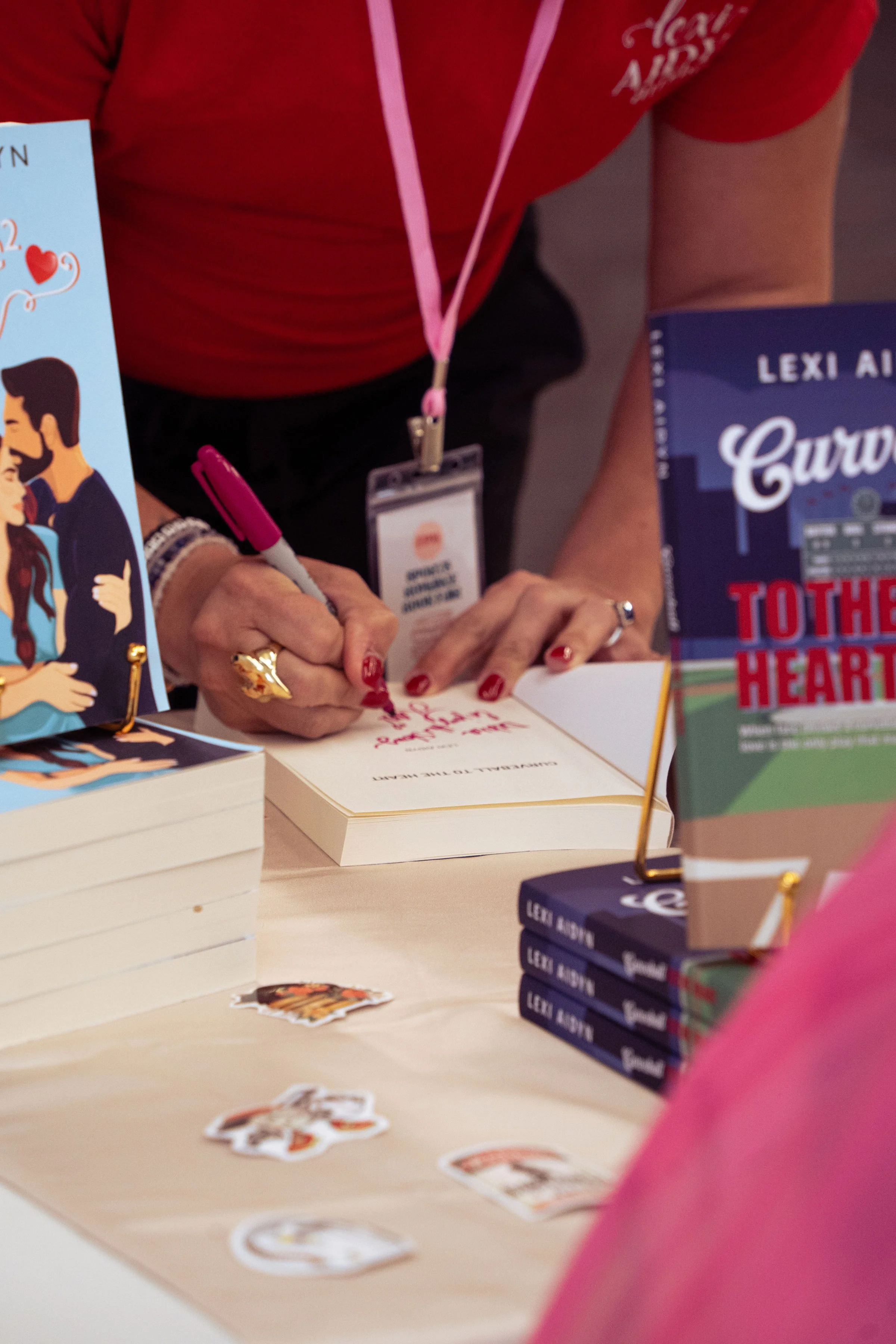 Author signing a book with a pink marker