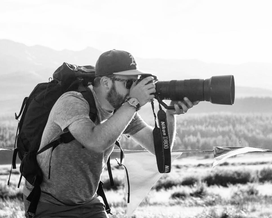 Image of photographer looking through a long lens camera