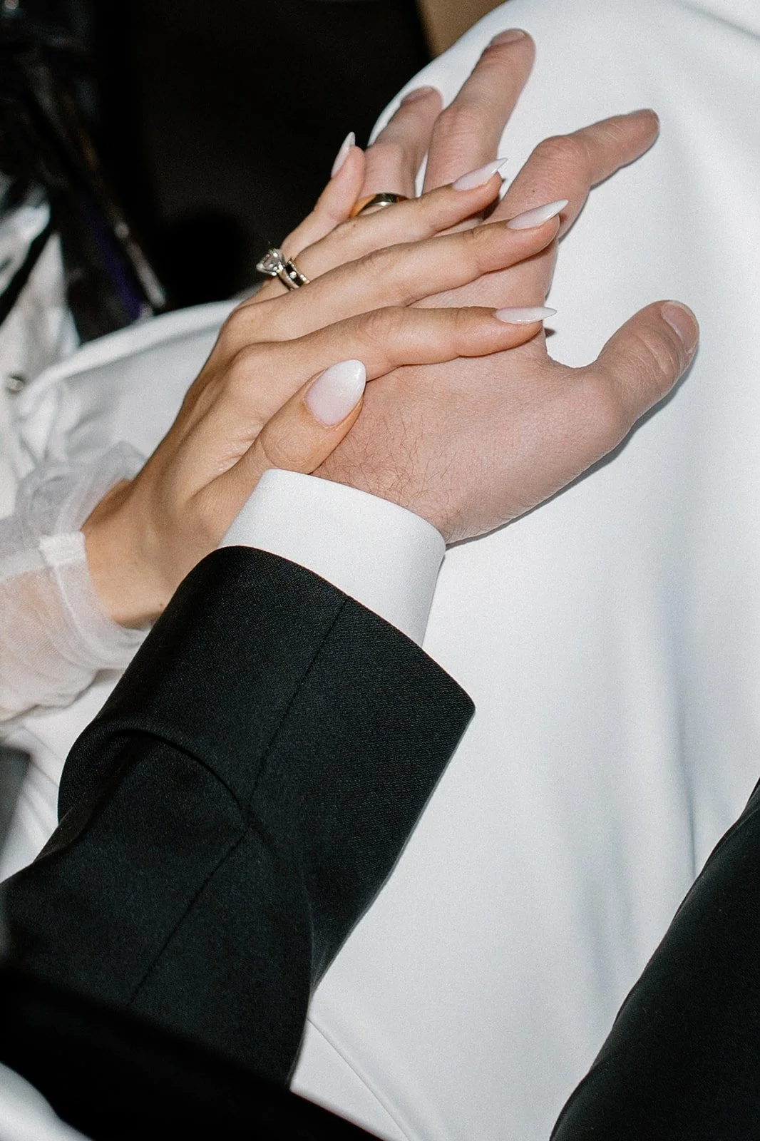 Close-up of a couple holding hands, with wedding rings, during a wedding ceremony.