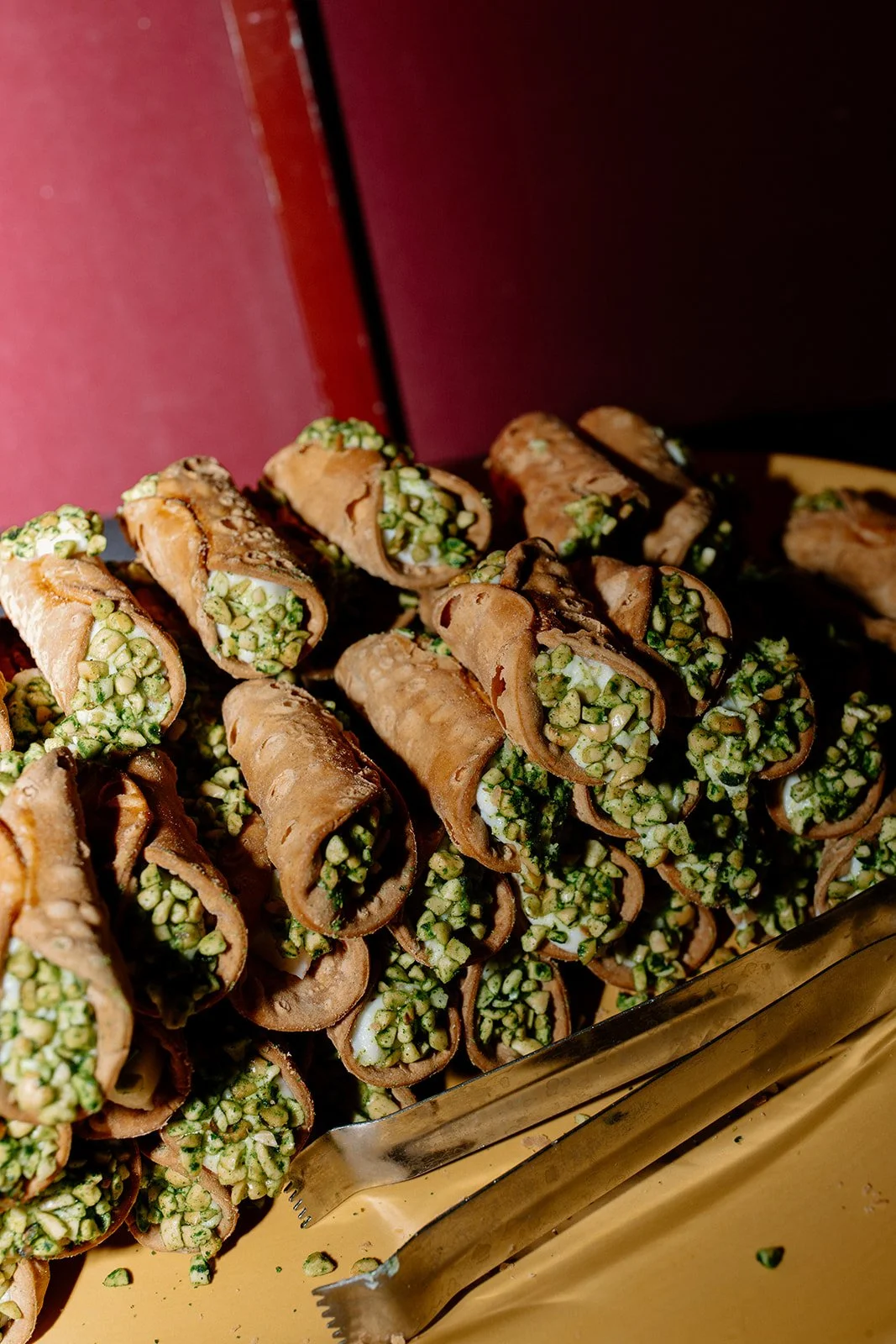 A tray of cannoli filled with chopped green pistachios.