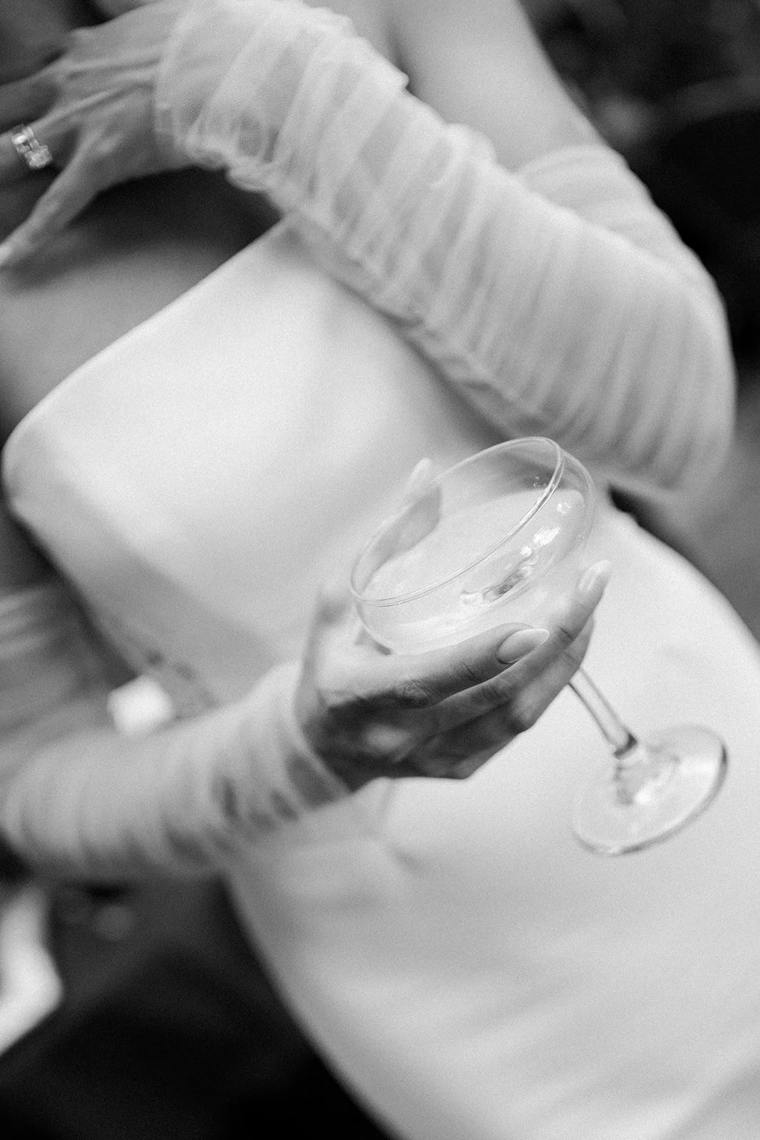 A person wearing a long-sleeved, striped shirt holding a cocktail glass with a drink inside.