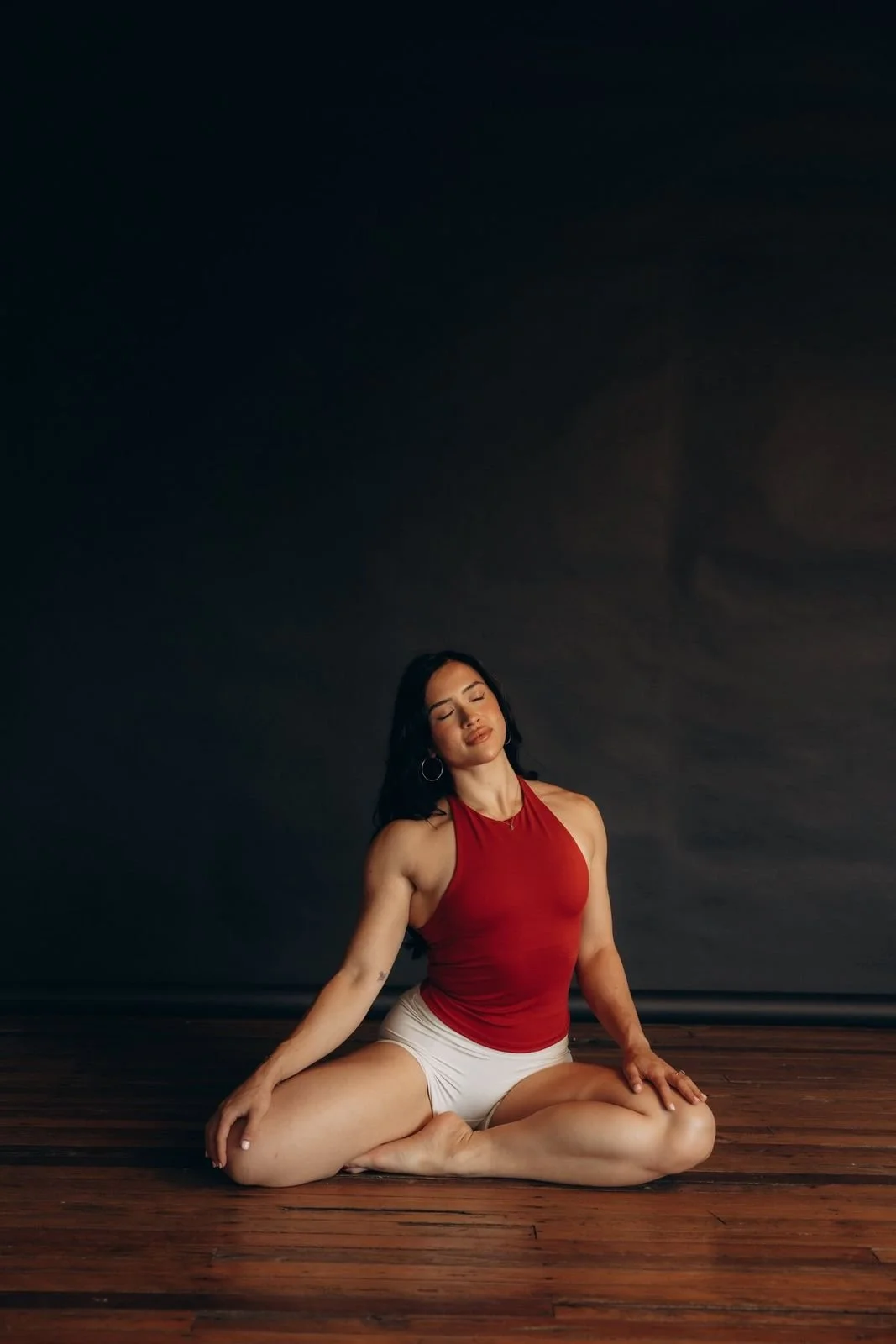 A woman sitting cross-legged with her eyes closed, calm and strong