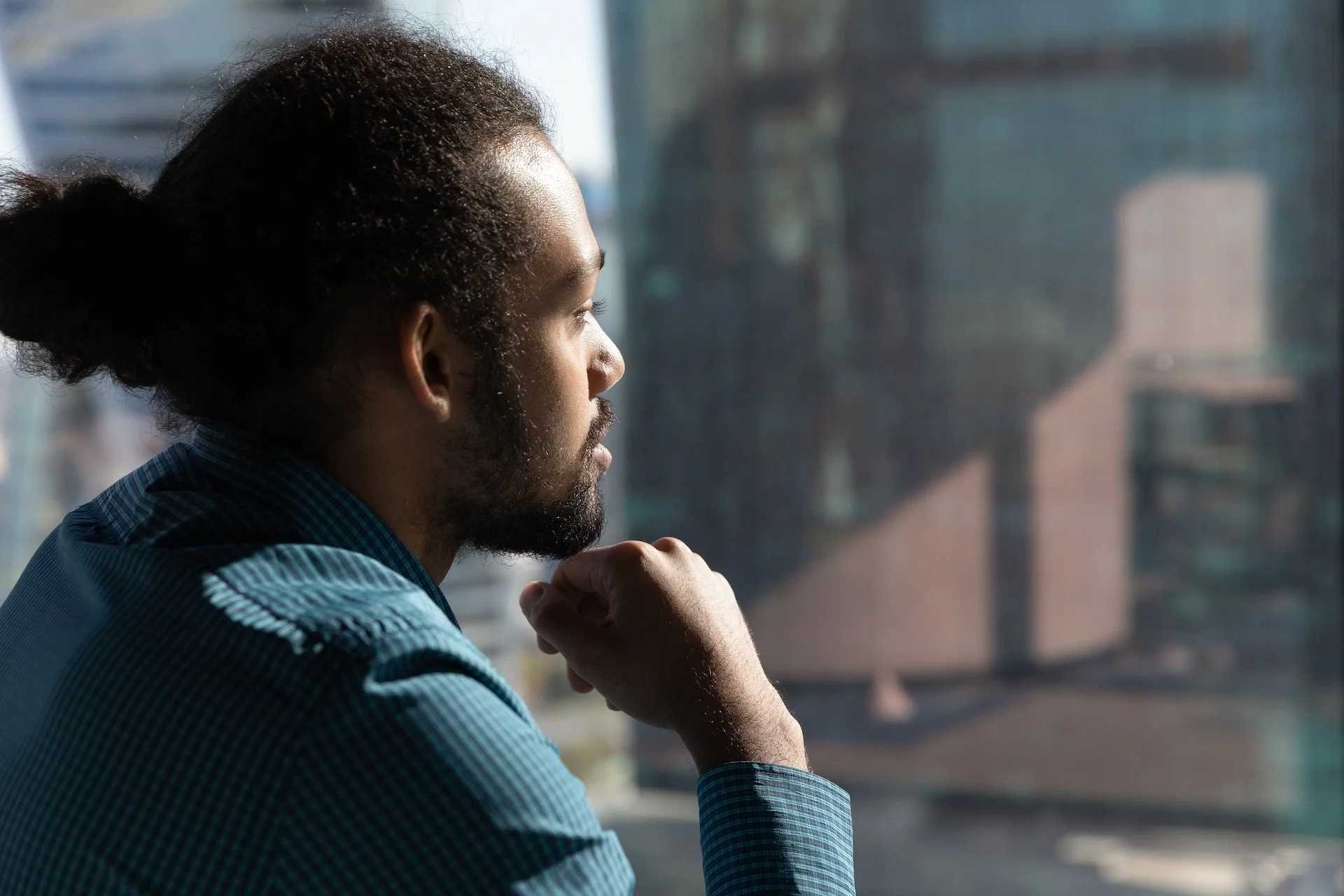 man looking out window in thoughtful reflection while considering personal growth or therapy options