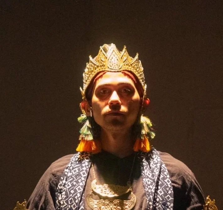 Dancer in casual clothing dancing or performing a pose against a plain background.