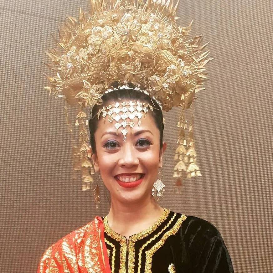 Woman in traditional black, gold and red costume, wearing golden headpiece