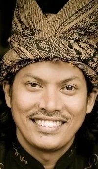 Smiling man wearing a traditional Indonesian patterned headwrap