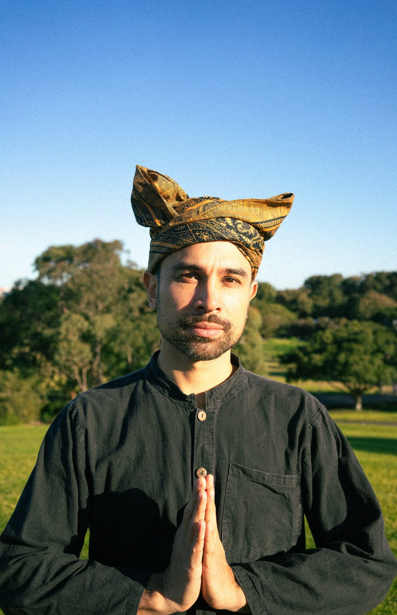 A man in traditional attire holding a microphone and smiling on stage.