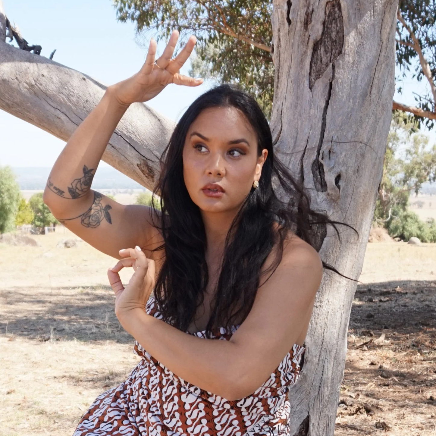 Woman in patterned batik costume, red scarf and gold necklace looking up