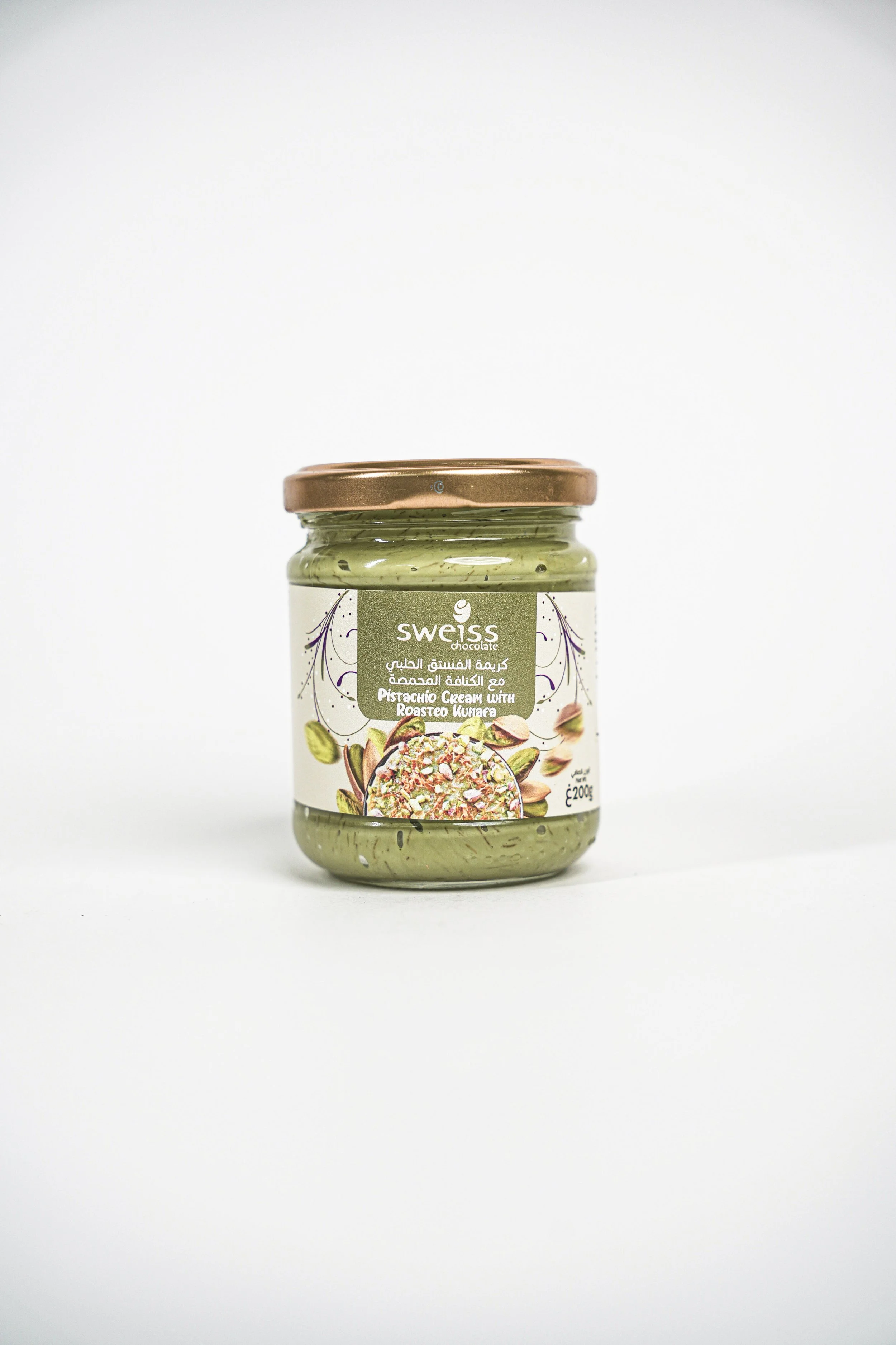 A jar of Swiss chocolate pistachio cream with roasted kunafa, featuring a label with pistachio illustrations and a photo of the dessert.