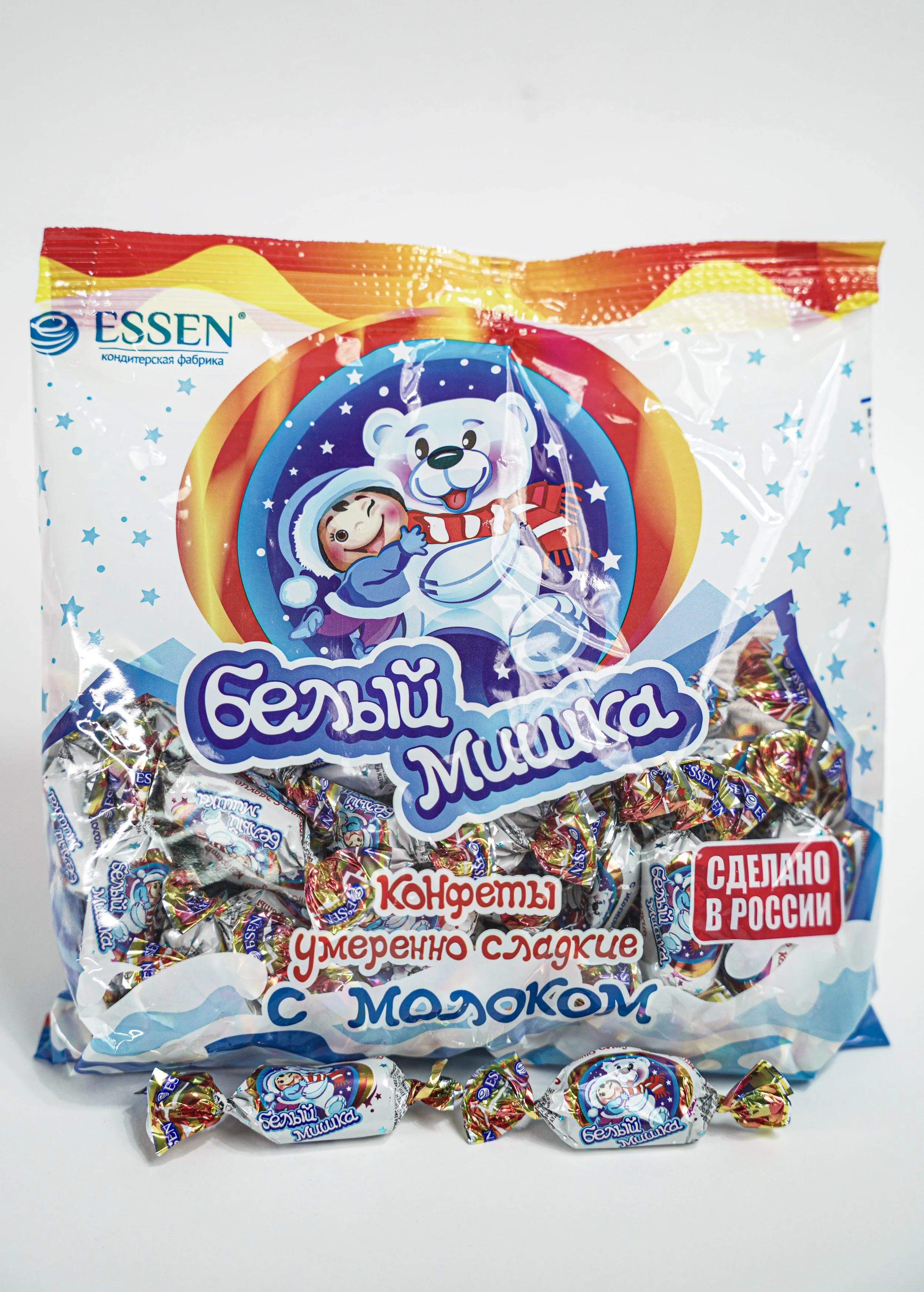 Bag of Russian milk-flavored candies with a cartoon polar bear and girl on the packaging, decorated with stars, with some candies spilled in front.