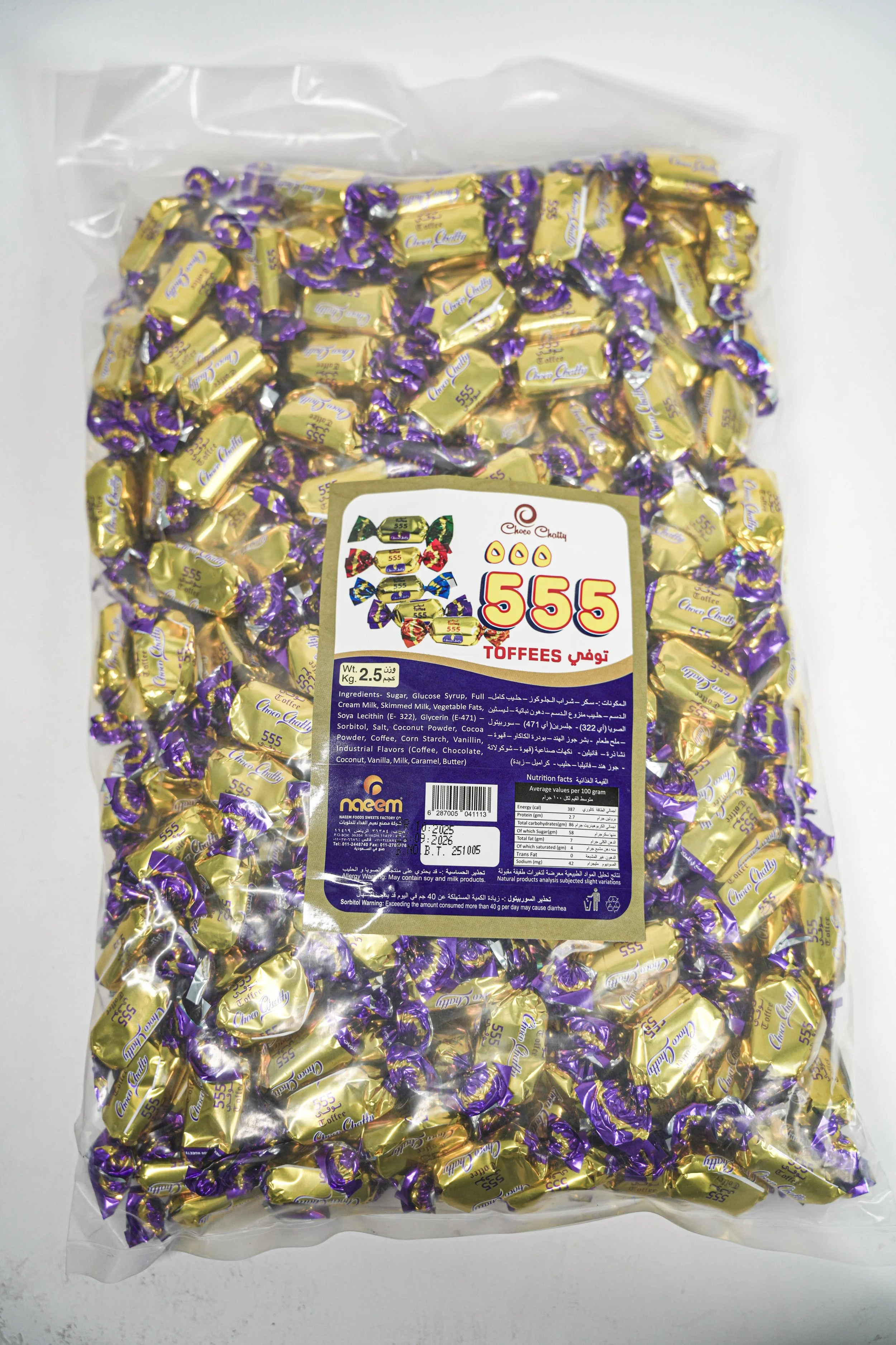 A large clear plastic bag filled with individually wrapped purple and gold candies labeled '555 Toffees.' The bag has a white and purple label with product details and ingredients.
