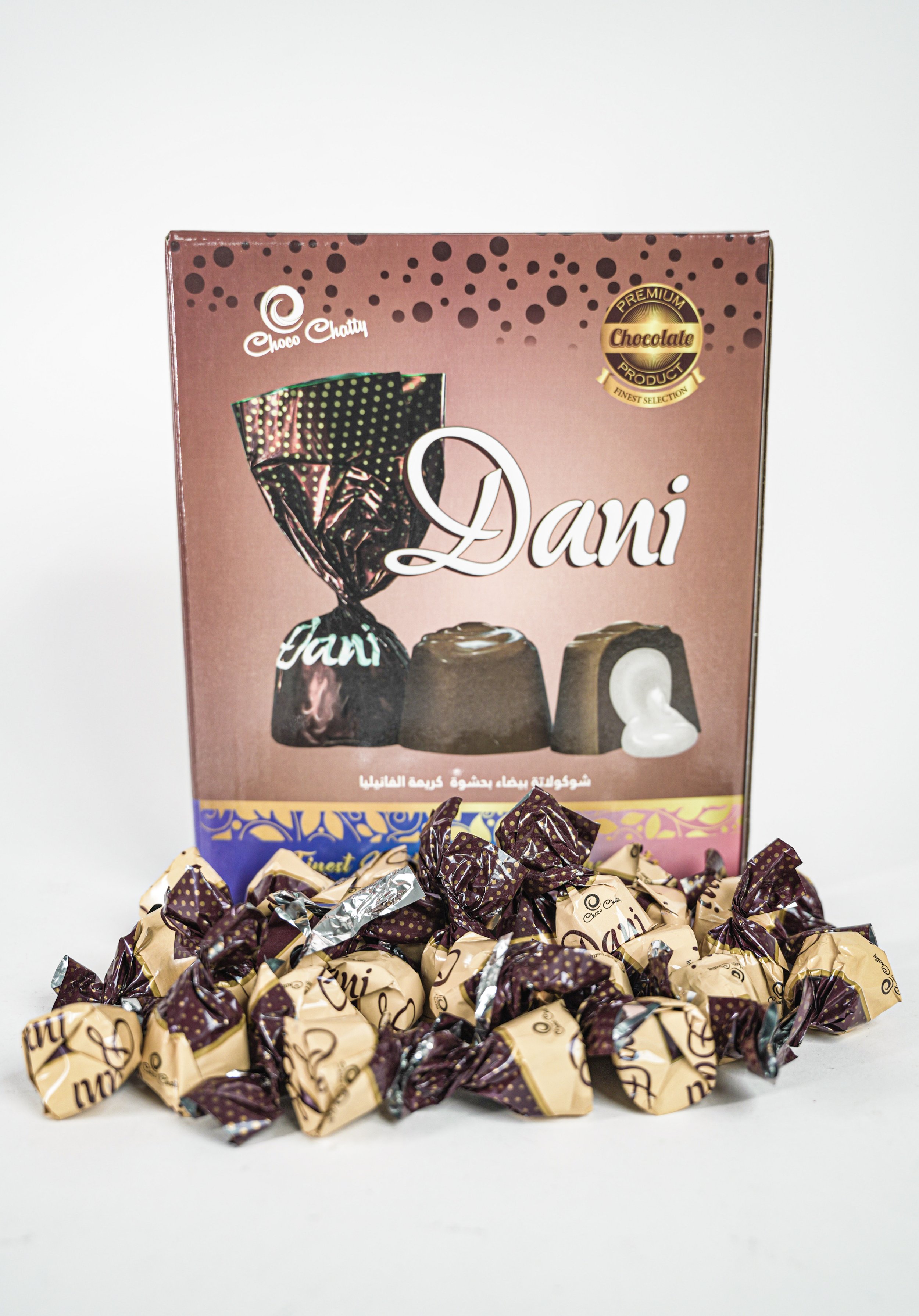 A box of chocolates labeled "Dani" with individually wrapped chocolates arranged in front of it.