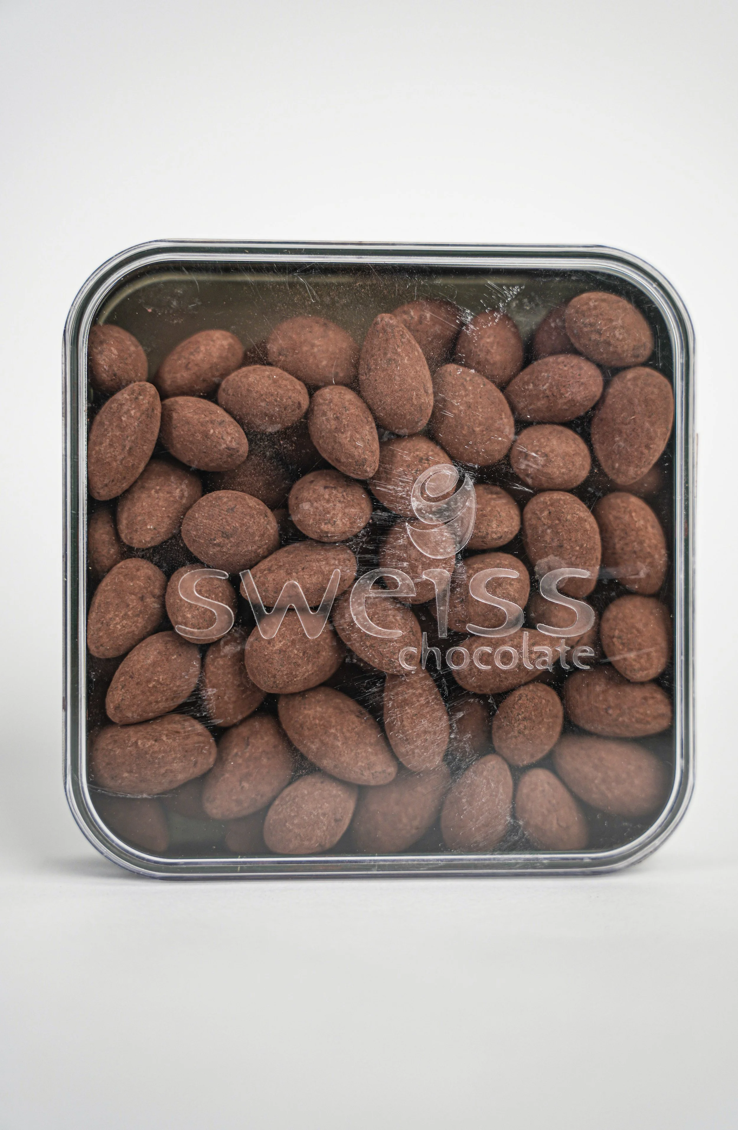 A clear square plastic container filled with chocolate-covered almonds.