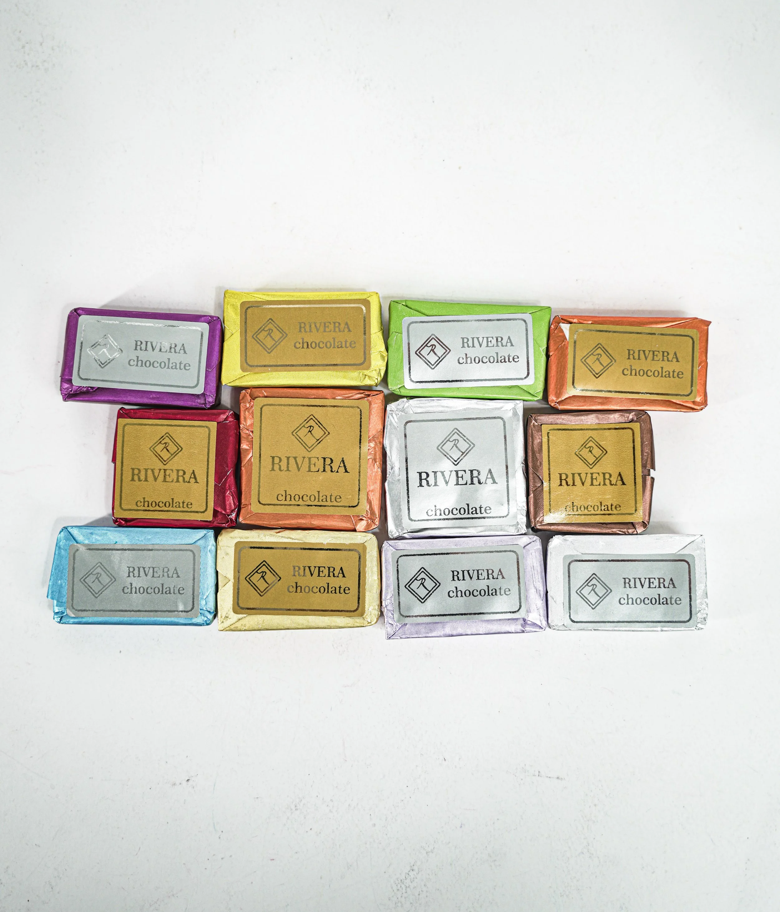Ten small wrapped pieces of chocolate in various colored foils arranged in three rows.