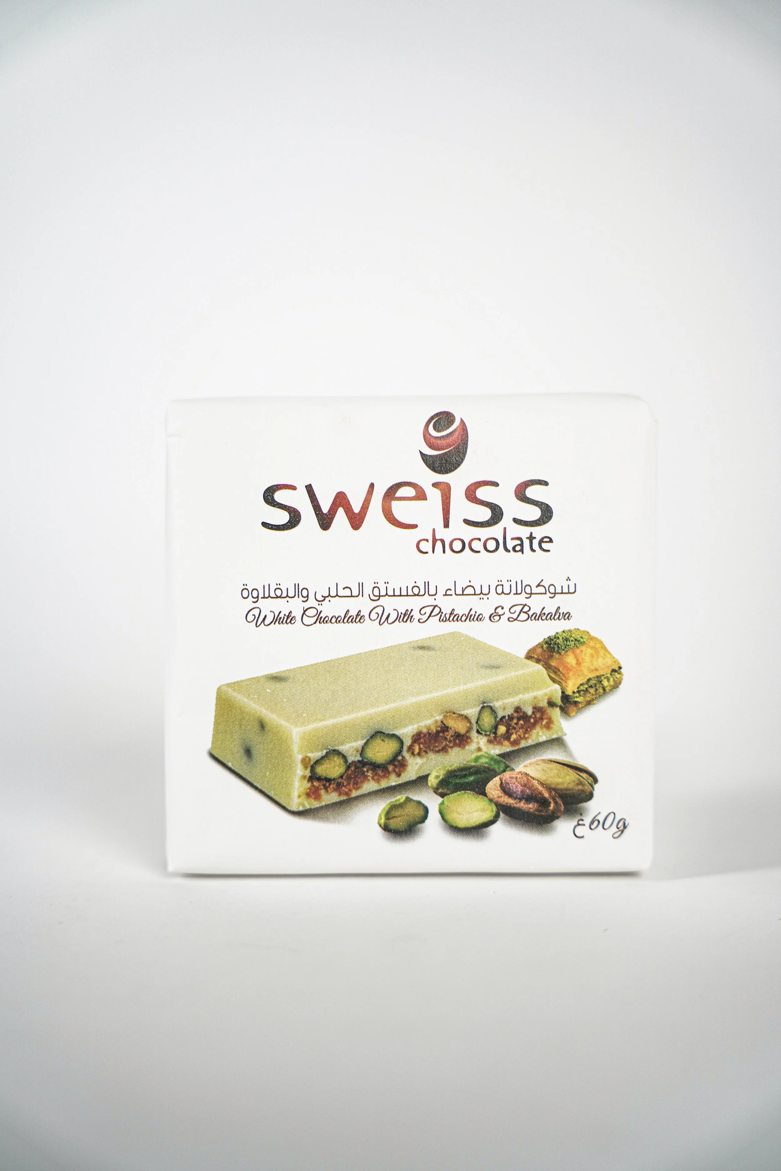 A box of Swiss chocolate with pistachios and baklava flavor, showing an image of a white chocolate bar with pistachios and baklava pieces on the packaging.