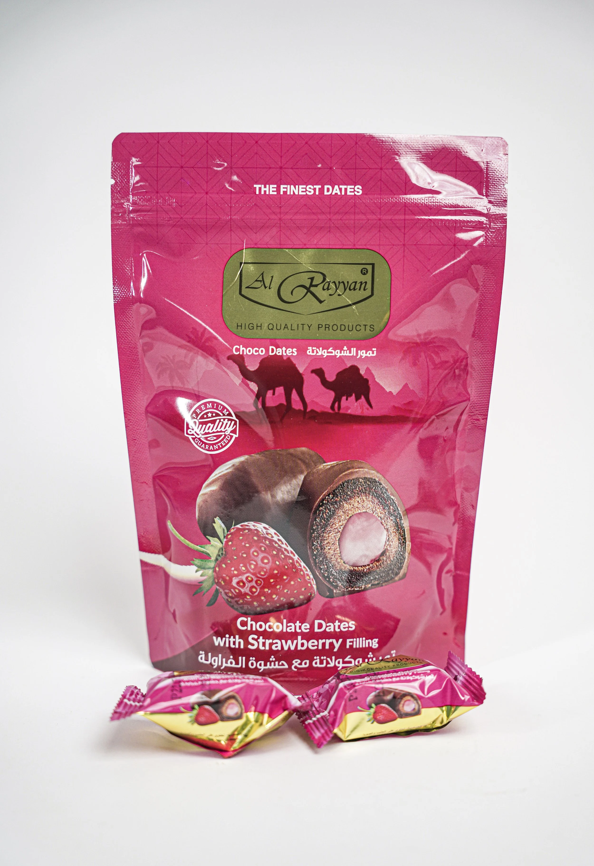 Pink package of Al Rayan chocolate dates with strawberry filling, with two individual wrapped candies in front, against a white background.