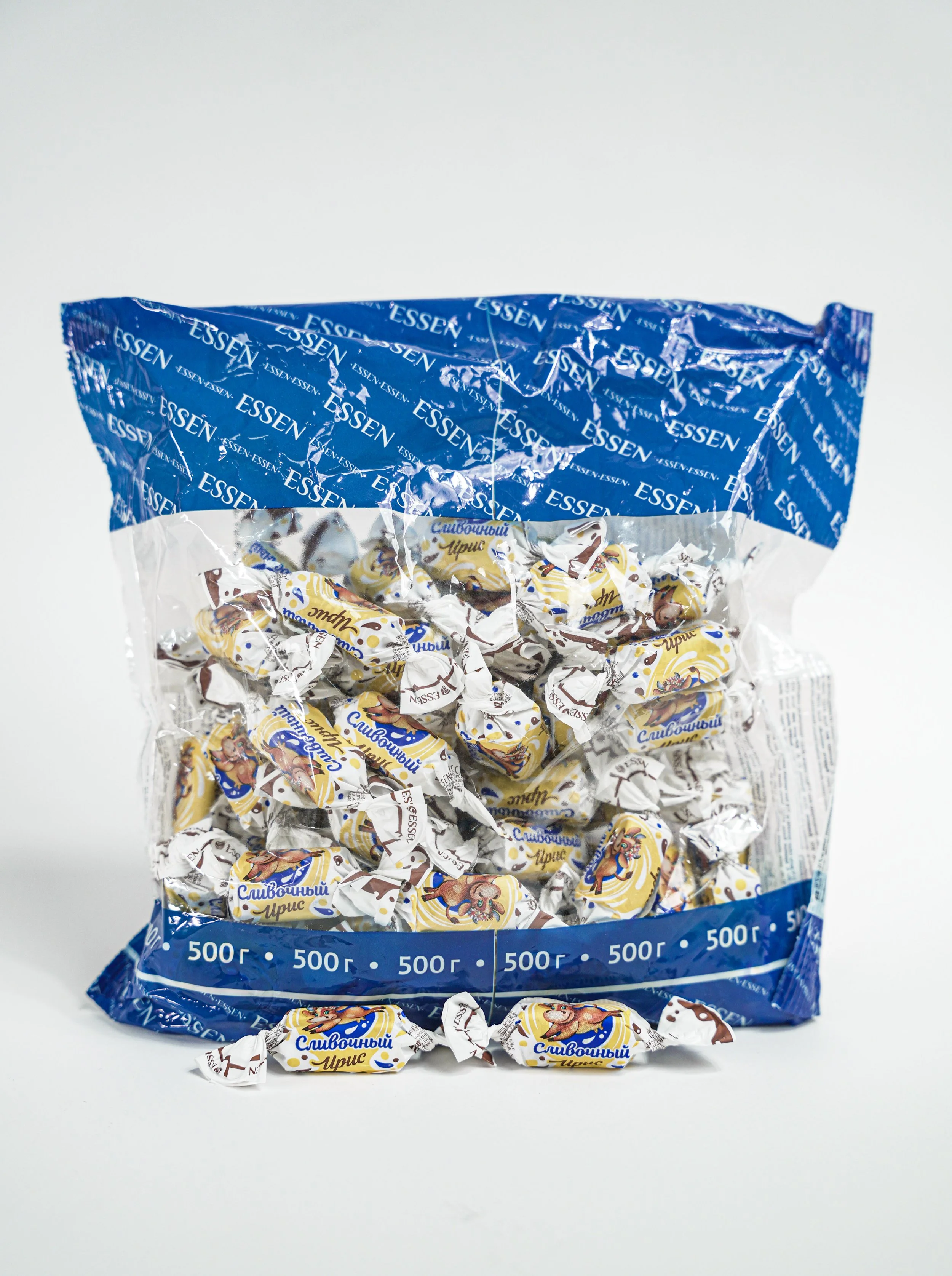 A blue and clear plastic bag of 500 grams of individually wrapped candies, with some candies outside the bag, featuring cartoon characters on the wrappers.