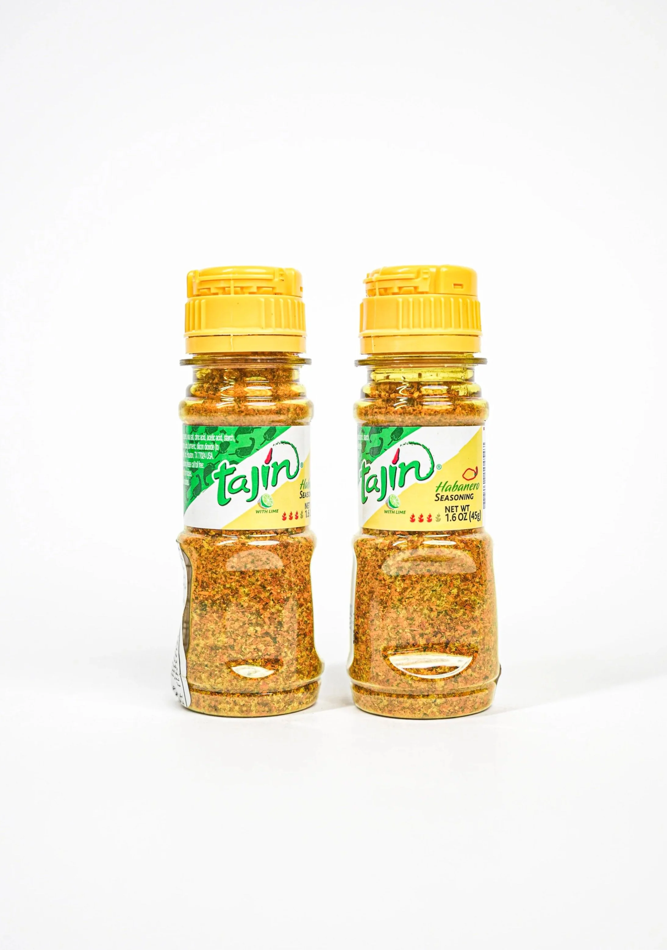 Two bottles of Tajín seasoning, one flavored with lime and the other with habanero, with yellow caps and green and yellow labels, set against a plain white background.