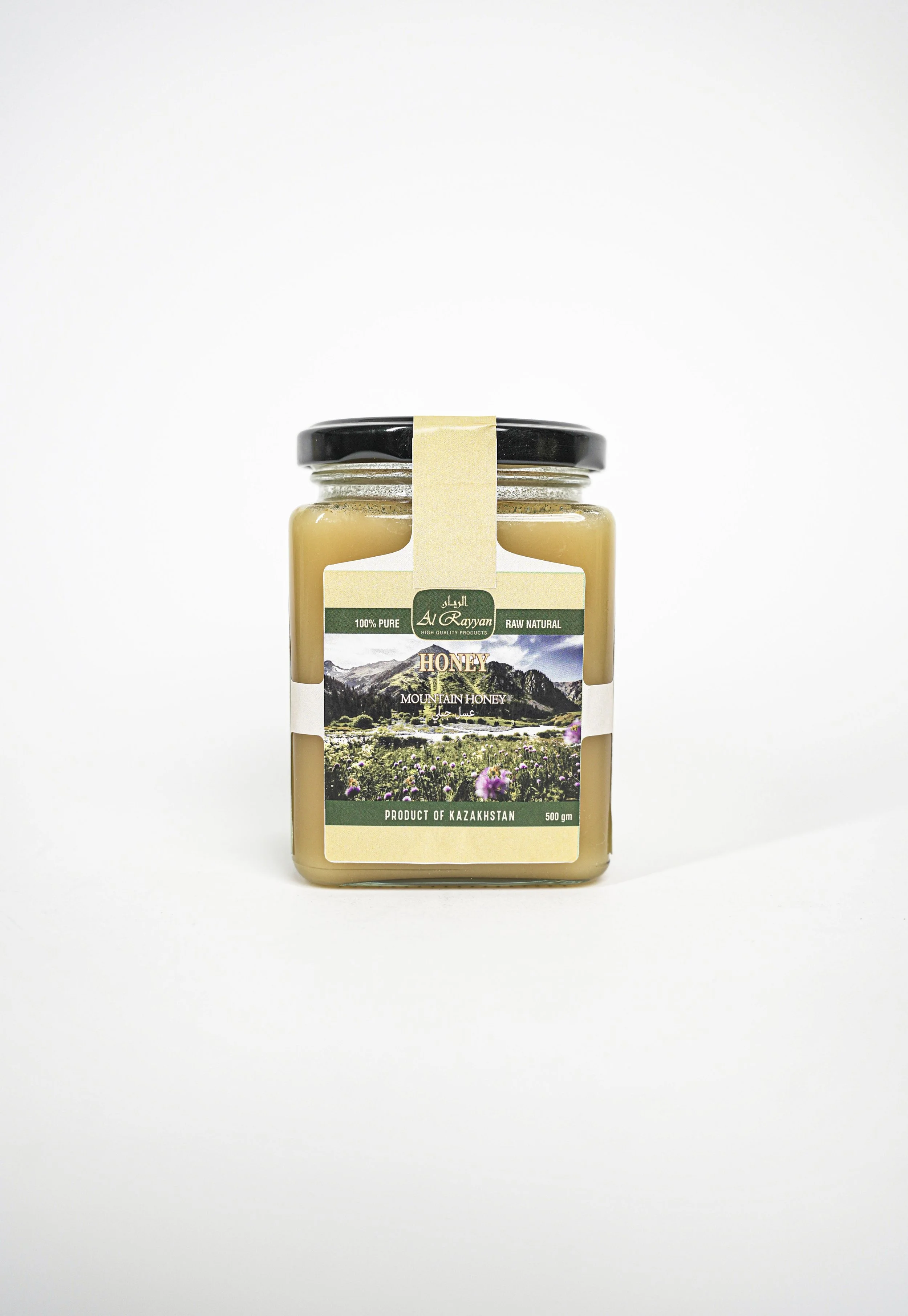 A jar of honey with a label showing mountains, flowers, and text indicating it is mountain honey from Kazakhstan.